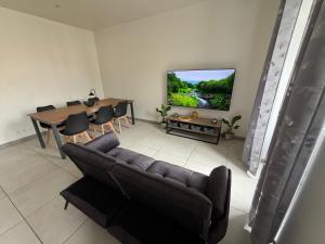 a living room with a couch and a table and a television at Entre Rivière et Sommets in Seix