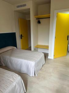 a room with two beds and a yellow door at Pensión Ariz in Basauri