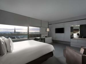 a bedroom with a large white bed and a large window at SO/ Vienna in Vienna
