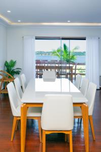 a dining room with a white table and white chairs at KoKo Beach - Wooden Green House in Vila Praia Do Bilene +16 photos