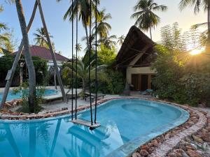 a pool in front of a house with palm trees at MONEA The Nest in Paje