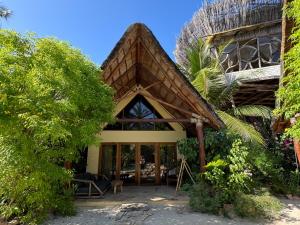 a house on the beach with a thatched roof at MONEA The Nest in Paje