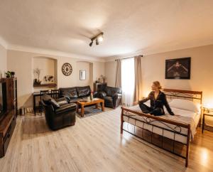 a woman sitting on a bed in a living room at Frauenberg Villa in Banská Štiavnica