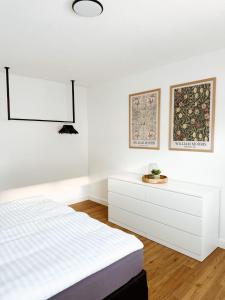 a white bedroom with a bed and a dresser at FeWo Reimer in Horn-Bad Meinberg