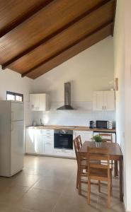 a kitchen with a table and a white refrigerator at Casa El Palmar - Playa y Jardín in El Palmar