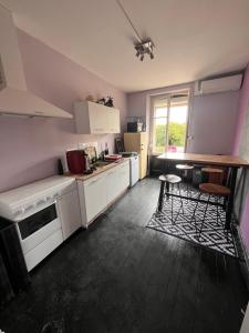 a kitchen with white cabinets and a table and chairs at Chambre bleue in Vigneulles-lès-Hattonchâtel