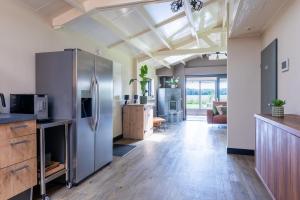 a kitchen with a stainless steel refrigerator and a living room at Chalet Achterbosch in Lieshout