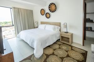 a bedroom with a white bed and a clock on the wall at Suites Santa Isabella in Ajijic
