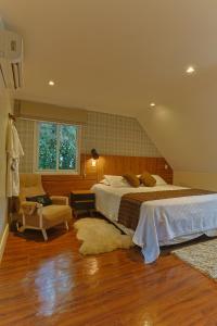 a bedroom with a bed and a chair and a window at Ti Voglio Bene in Campos do Jordão