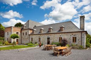 ein großes Steinhaus mit einem Tisch und Stühlen in der Unterkunft Château-ferme de Pondrome in Beauraing