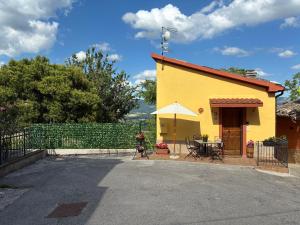 a small yellow house with a table and umbrella at Casa Broglia in Castel Santa Maria