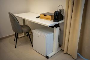 a white desk with a chair next to a table with a microwave at B&B Hipponion in Vibo Valentia