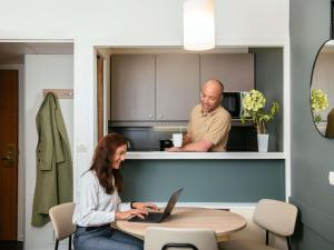 a man and a woman sitting at a table with a laptop at Aparthotel Adagio La Défense Le Parc in Courbevoie