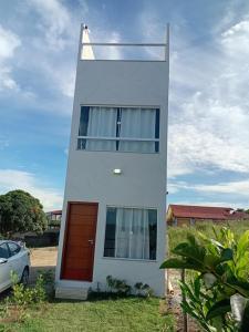 a white house with a red door and a car at Triplex com linda vista para o mar de Parati Anchieta ES in Anchieta