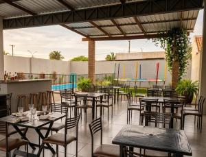 a restaurant with tables and chairs and a pool at Espaço Manacá in Dourados