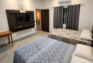 a hotel room with two beds and a flat screen tv at Espaço Manacá in Dourados