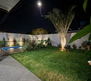 a backyard at night with a palm tree and a fence at Espaço Manacá in Dourados +1 photo