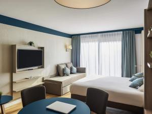 a hotel room with a bed and a tv at Aparthotel Adagio Monaco Palais Joséphine in Beausoleil