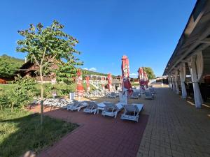 a group of lounge chairs and umbrellas on a patio at La Hacienda in Cheţani +45 photos