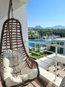 a swinging chair on a balcony with a view of a pool at Sun Valley 2-bedroom apartment in Nicosia International Airport