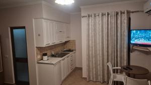 a kitchen with white cabinets and a sink and a television at Amras house in Durrës