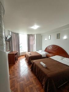 a hotel room with two beds and a desk at Hotel Plaza Grau in Trujillo
