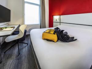 a hotel room with a bed with a yellow bag on it at Ibis Styles Strasbourg Centre Gare in Strasbourg