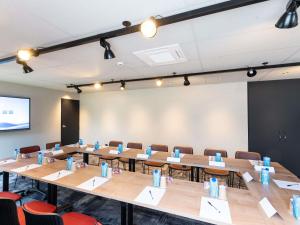 a conference room with tables and chairs and a screen at Ibis Orleans La Chapelle Saint Mesmin in La Chapelle-Saint-Mesmin