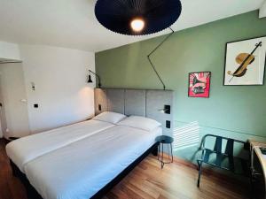 a bedroom with a large white bed and green walls at ibis Beauvais Aéroport in Beauvais