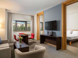 a hotel room with a bed and a desk with a television at Novotel Kayseri in Kayseri