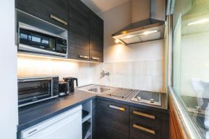 a kitchen with black cabinets and a microwave and a sink at Studio 28 Kaprun inkl Sommerkarte in Kaprun