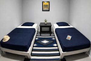 zwei Einzelbetten in einem Zimmer mit einem Tisch in der Unterkunft Hostel Auikyani in Cozumel