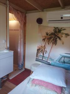 a bedroom with a bed and a painting of palm trees at Tiny house tout inclus in Fronton