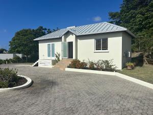 a small white house with a driveway at The Cottage in Saint Georgeʼs