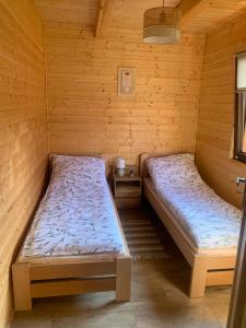 a room with two beds in a wooden cabin at Domek letniskowy Remix in Zwierzyniec