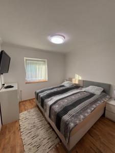 a bedroom with a bed and a flat screen tv at Bozóki Apartman in Kiskunmajsa