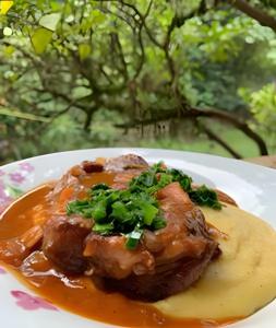a plate of food with a piece of meat and sauce at Piccola Cucina: Casa centenária Vale dos Vinhedos in Garibaldi
