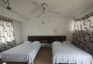 two beds in a room with two windows at Hotel Caleta Bor Acapulco in Acapulco