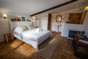 a bedroom with a large white bed and a fireplace at Maison Roque in Sannes