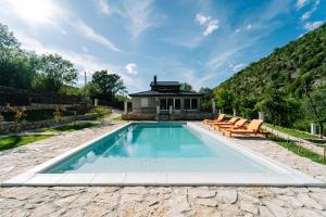 a swimming pool with chairs and a house at Villa Vrelo Oasis in Malo Polje