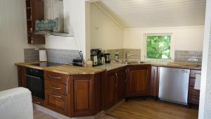 a kitchen with wooden cabinets and a white dishwasher at HagestadHytteutleie Wallhall in Birkenes +10 photos