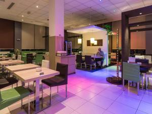 a restaurant with tables and chairs and a man sitting at a counter at ibis Oran les Falaises in Oran