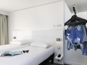 a bedroom with a bed with a book and glasses on it at Ibis Styles Menton Centre in Menton