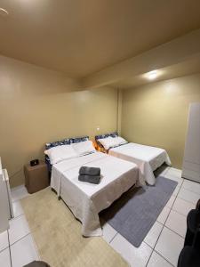 a room with two beds with white sheets at Refugio Centrico Studio 2 in Ciudad del Este