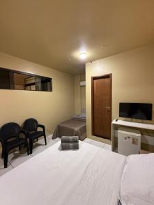 a bedroom with a bed and a television and chairs at Refugio Centrico Studio 2 in Ciudad del Este +10 photos
