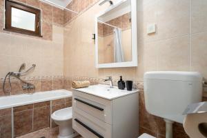a bathroom with a sink and a toilet and a tub at Apartman Noemi in Kukci +24 photos