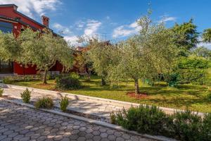 a garden with trees in front of a red building at Apartman Noemi in Kukci