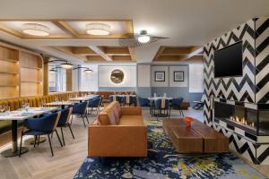 a restaurant with tables and chairs and a fireplace at Hotel Indigo Detroit North - Troy by IHG in Troy