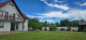 a white house with a yard with grass and trees at Pensiunea Casa Mădă in Baia de Fier
