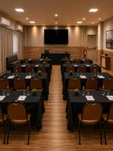 a conference room with tables and chairs and a screen at ibis Catanduva in Catanduva
